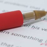 Close-up of typed manuscript page with corrections and red pen