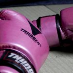A pair of pink boxing gloves sitting on a beige table.