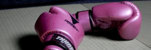 A pair of pink boxing gloves sitting on a beige table.