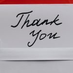 White note saying "Thank you" against a background of red envelopes.