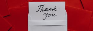 White note saying "Thank you" against a background of red envelopes.