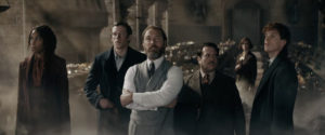 Screenshot from "Fantastic Beasts: The Secrets of Dumbldore" of several people in an old classroom: A Black woman, three white men, and a white woman in the background